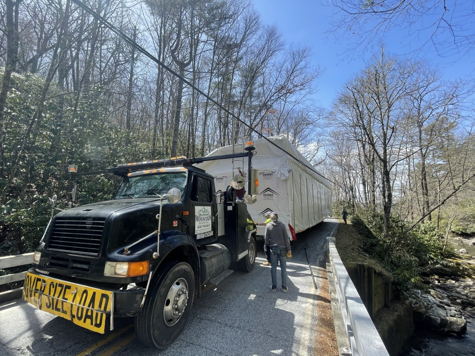Toter truck guiding a home across a small bridge