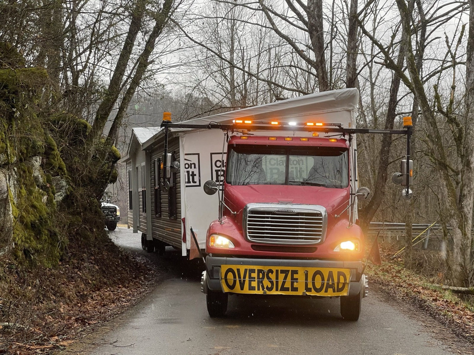 Red toter pulling a home through a wooded road